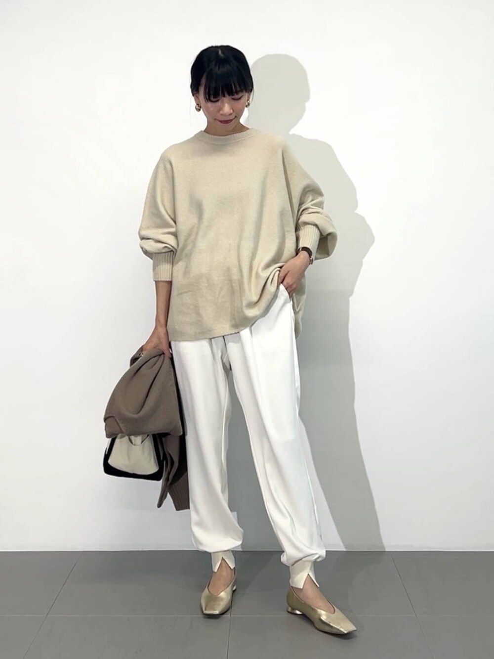 ホワイト系のトートバッグ、ゴールド系のパンプス、ホワイト系のその他パンツを着用したレディースの冬コーディネートの6枚目の写真