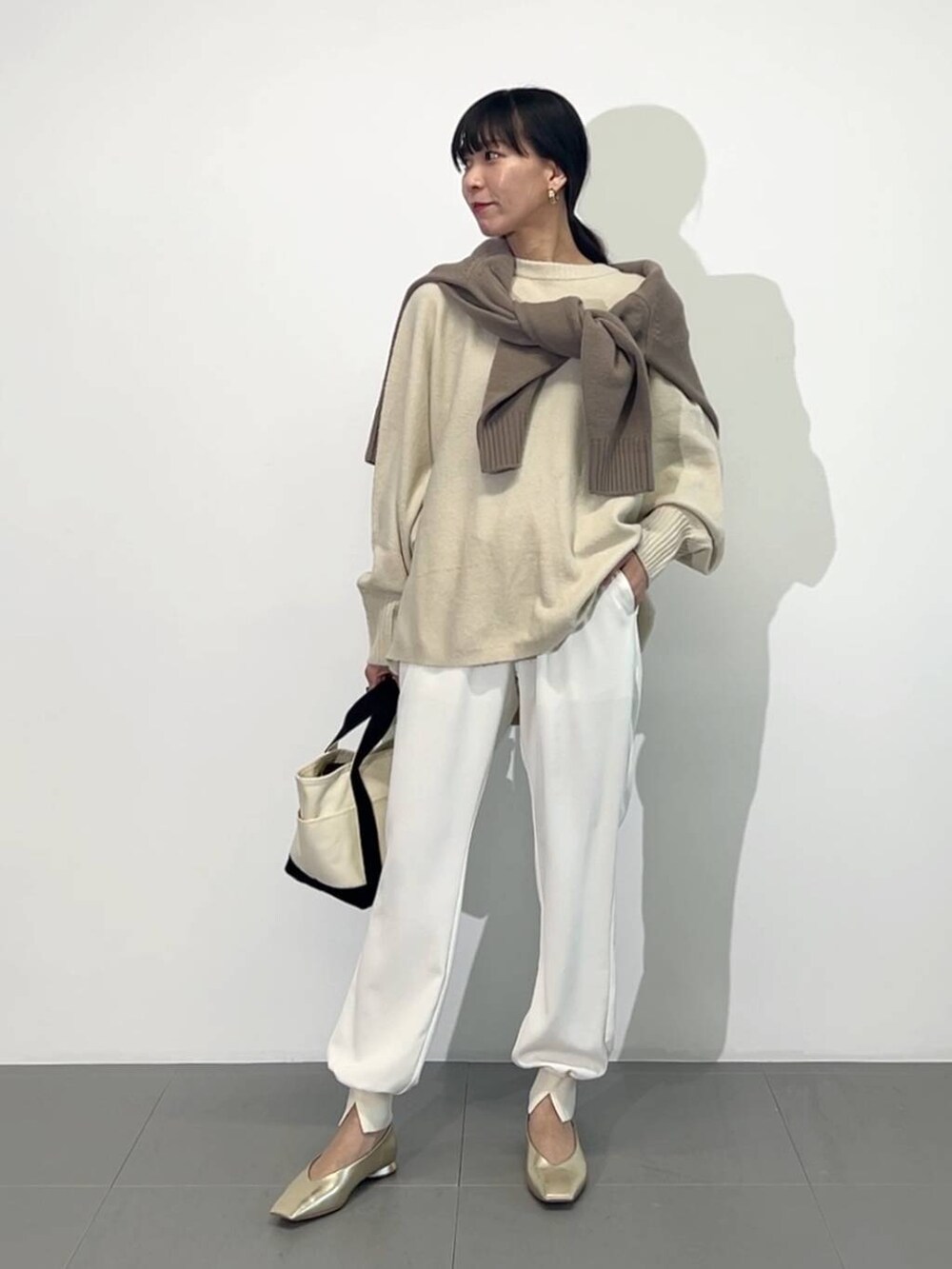 ホワイト系のトートバッグ、ゴールド系のパンプス、ホワイト系のその他パンツを着用したレディースの冬コーディネートの7枚目の写真