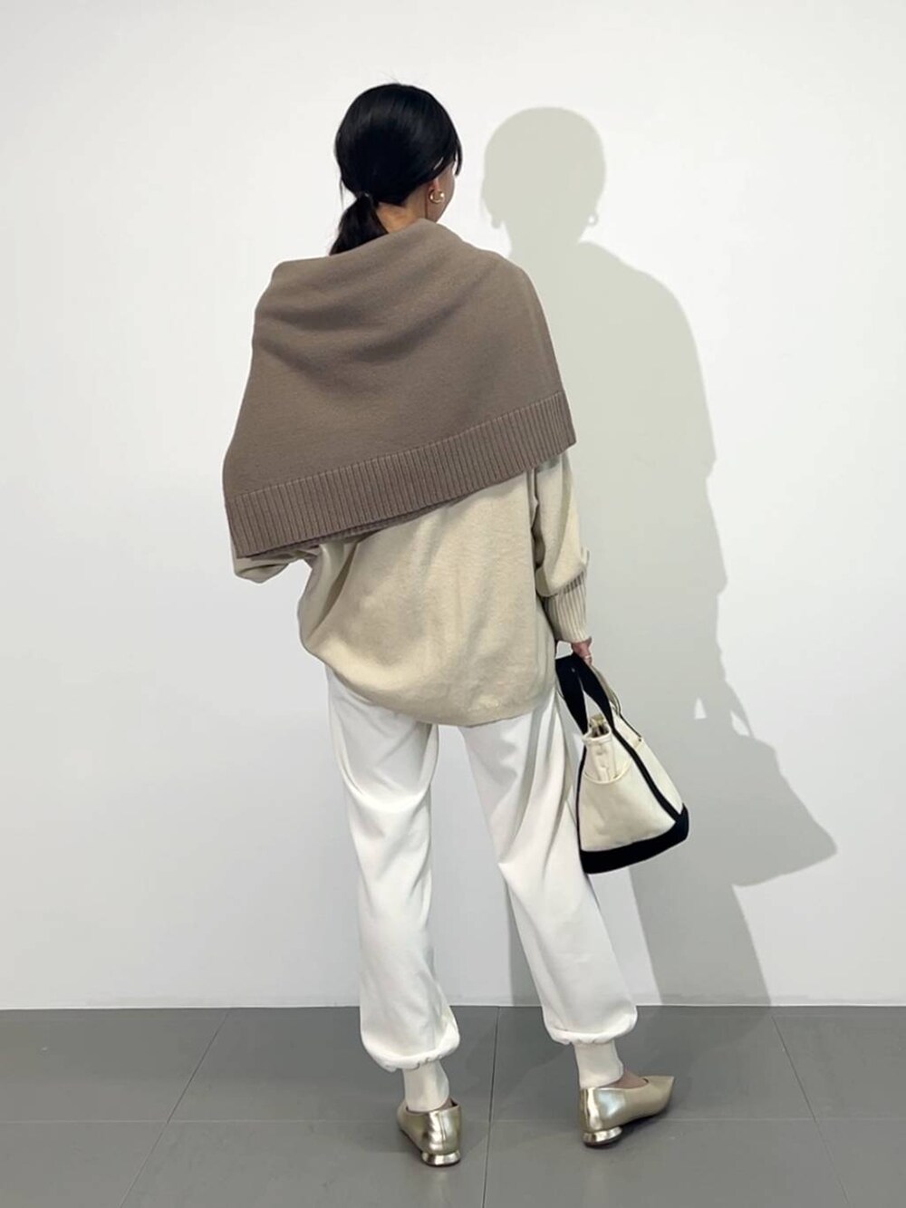 ホワイト系のトートバッグ、ゴールド系のパンプス、ホワイト系のその他パンツを着用したレディースの冬コーディネートの3枚目の写真