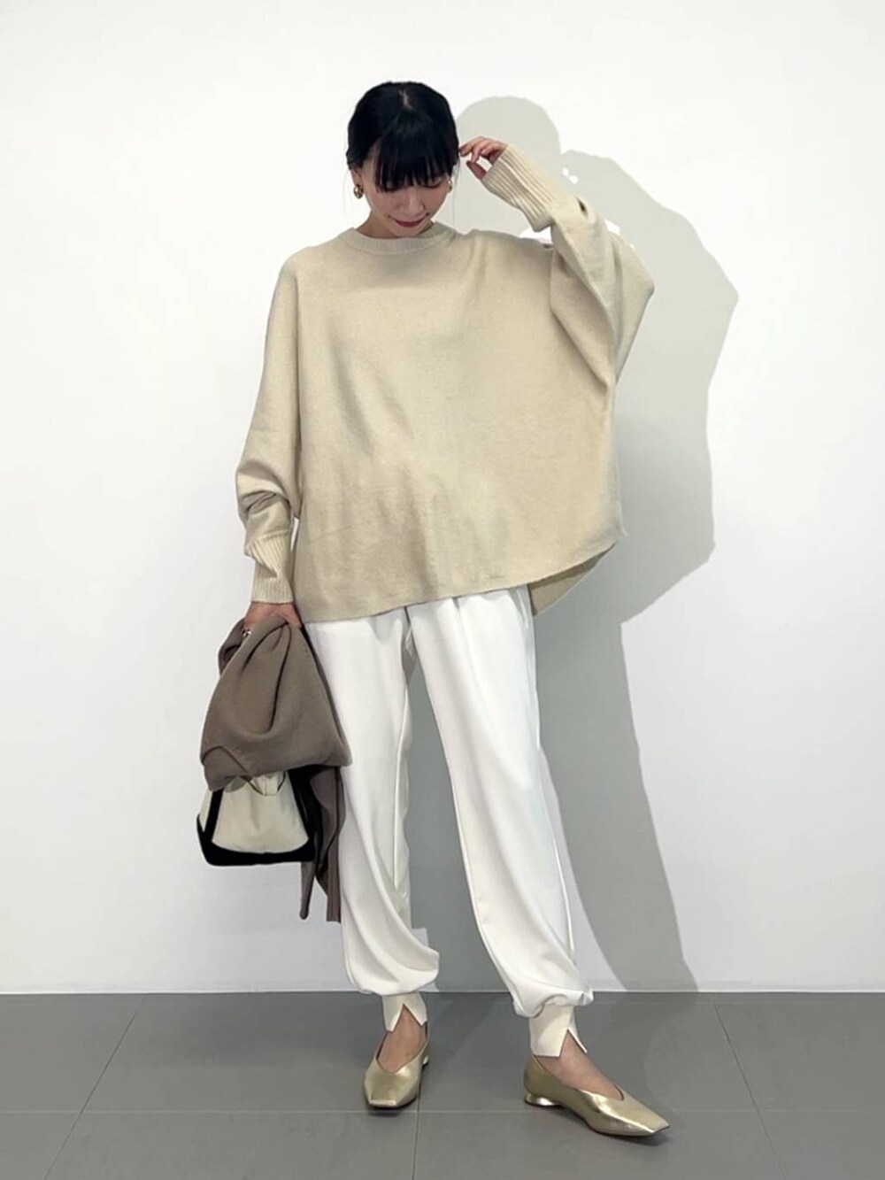 ホワイト系のトートバッグ、ゴールド系のパンプス、ホワイト系のその他パンツを着用したレディースの冬コーディネートの4枚目の写真