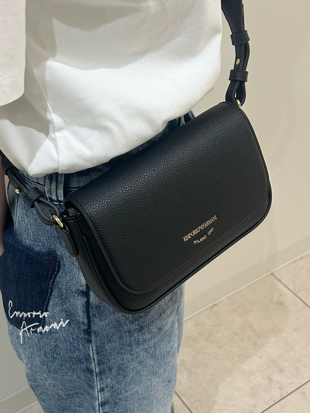 ホワイト系のTシャツ/カットソー、ブラック系のショルダーバッグ、グレー系のキャップを着用したレディースの春コーディネートの3枚目の写真