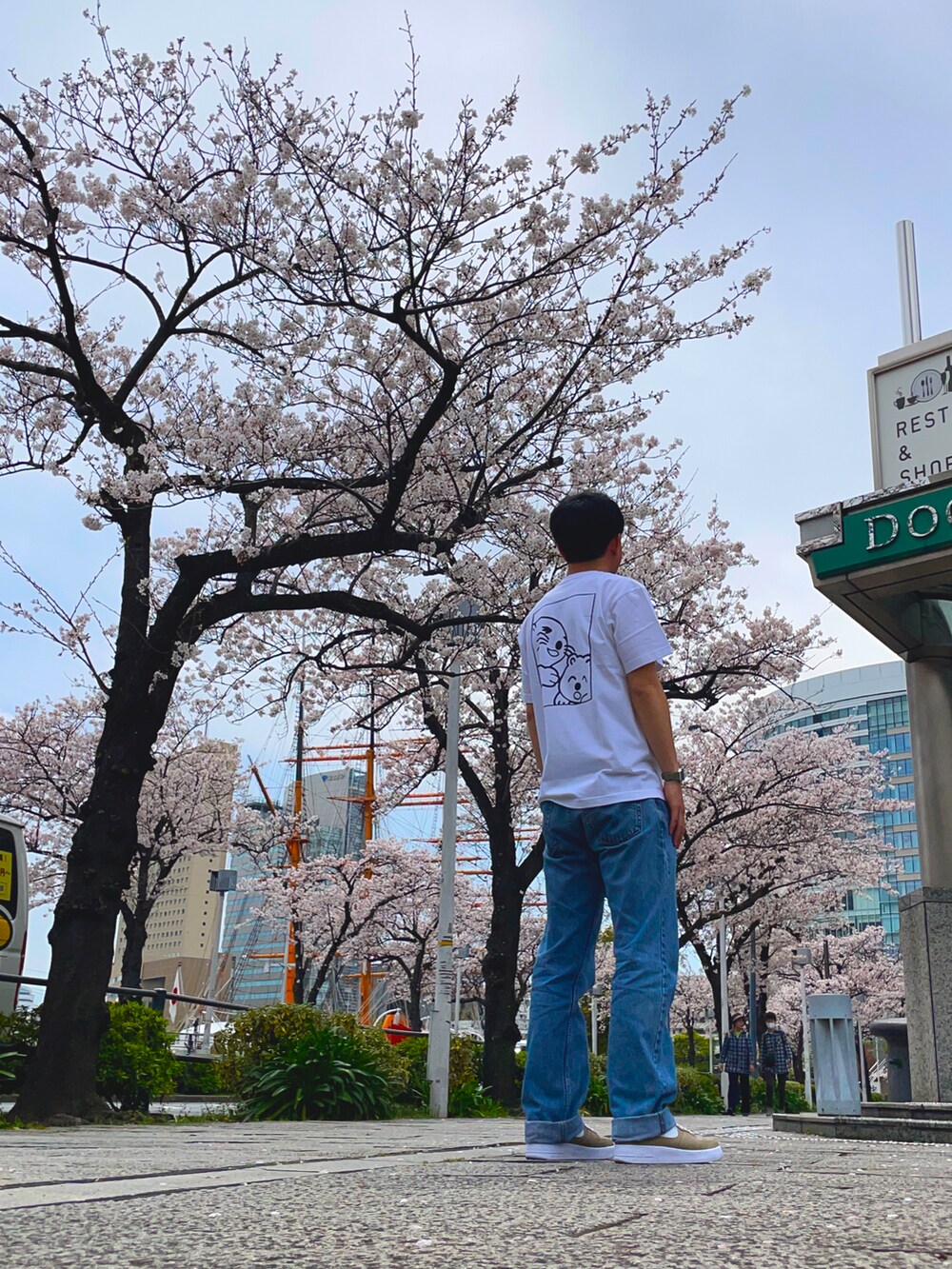 ブルー系のデニムパンツ、ベージュ系のスニーカー、ホワイト系のTシャツ/カットソーを着用したメンズの春コーディネートの2枚目の写真