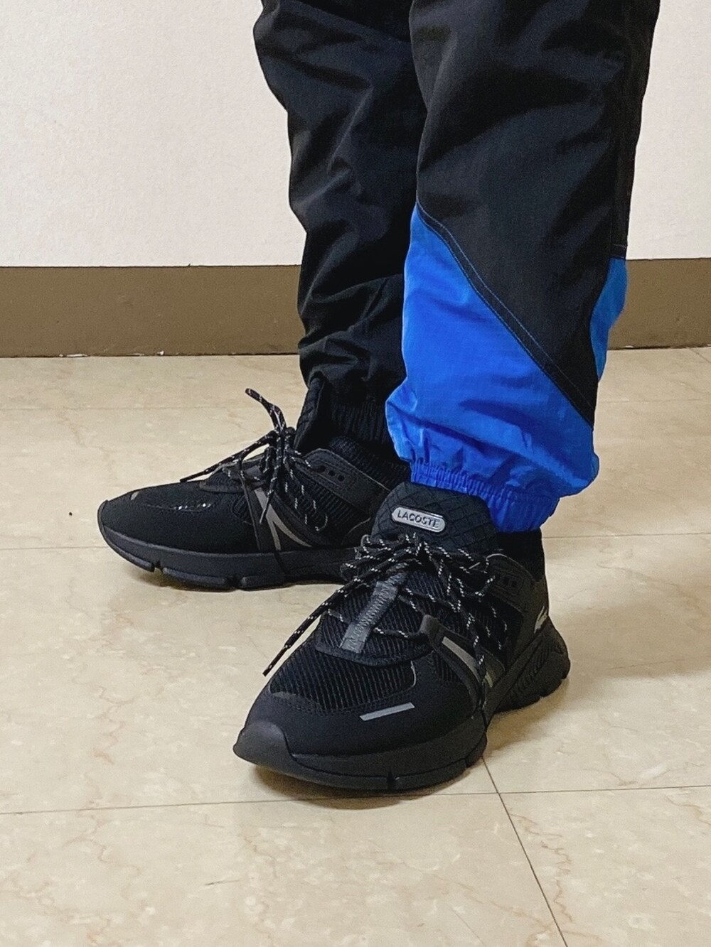 「ロンT、白ロンT、トラックパンツ、スニーカー、黒スニーカー、ショルダーバッグ、ラコステ」｜「LACOSTEのメンズ L003 0722 1（スニーカー、ブラック系）」を使った、maaashiiiiiiさん（メンズ・167cm）の春コーディネートの6枚目の写真