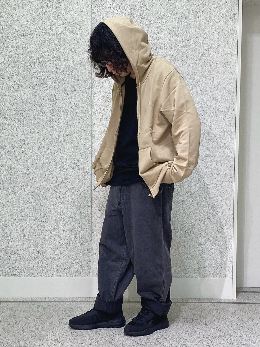 ブラック系のスニーカー、ブラック系のデニムパンツ、ベージュ系のパーカーを着用したメンズの秋コーディネートの2枚目の写真