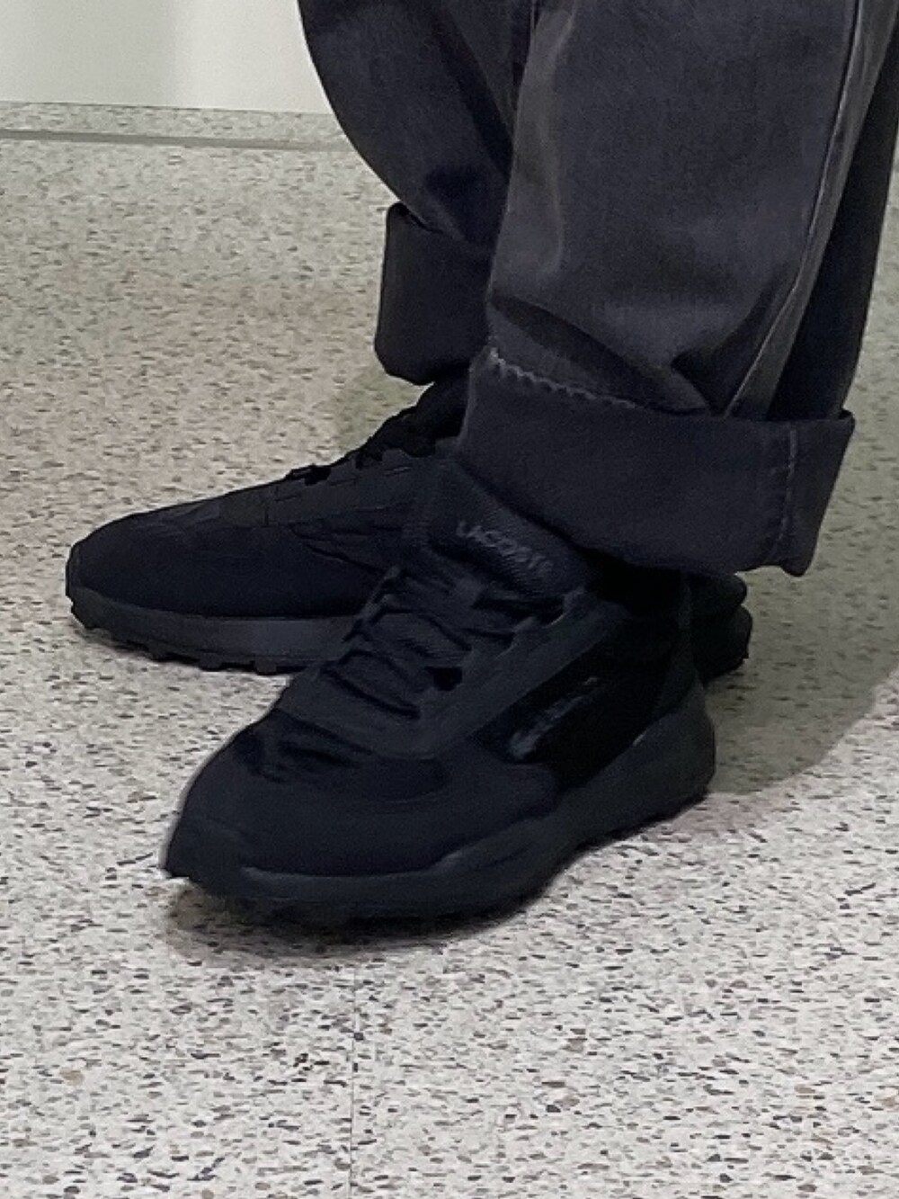 ブラック系のスニーカー、ブラック系のデニムパンツ、ベージュ系のパーカーを着用したメンズの秋コーディネートの5枚目の写真