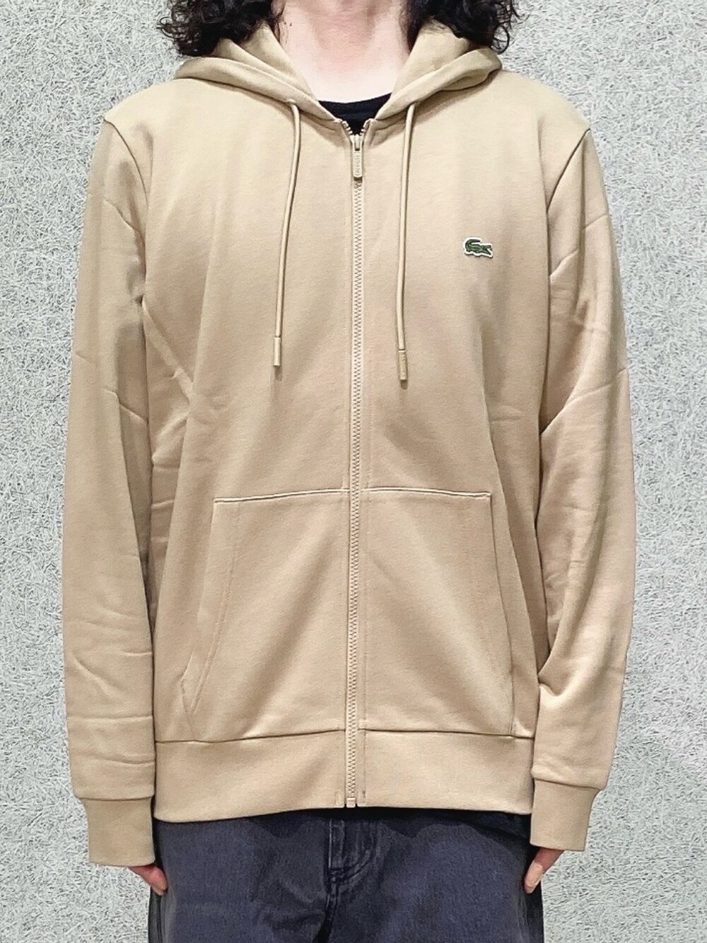 ブラック系のスニーカー、ブラック系のデニムパンツ、ベージュ系のパーカーを着用したメンズの秋コーディネートの4枚目の写真