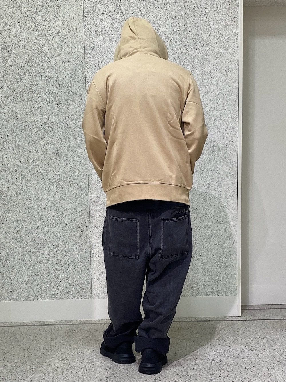 ブラック系のスニーカー、ブラック系のデニムパンツ、ベージュ系のパーカーを着用したメンズの秋コーディネートの3枚目の写真