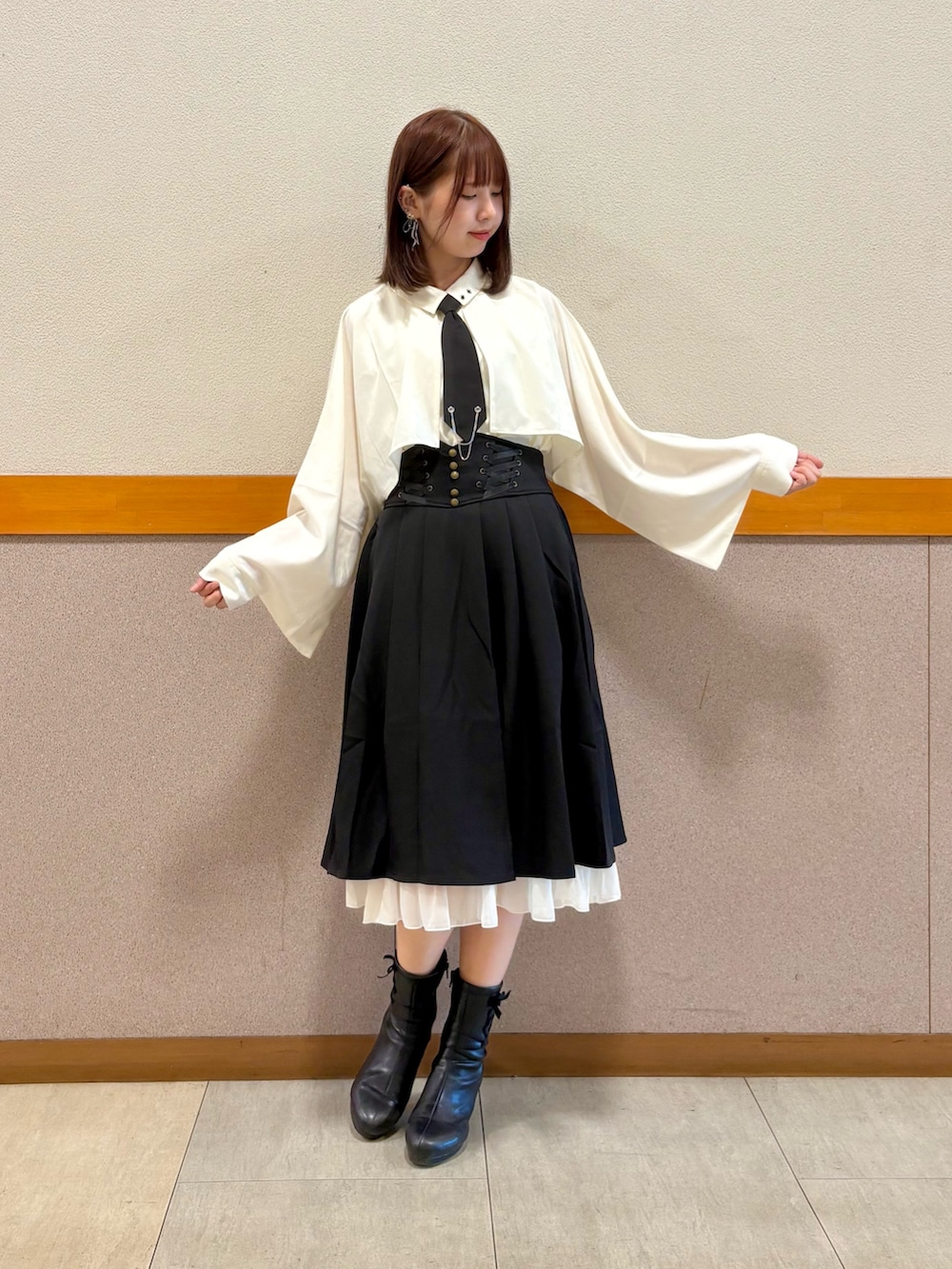 レッド系のトレンチコート、ホワイト系のシャツ/ブラウス、ブラック系のスカートを着用したレディースの秋コーディネートの3枚目の写真