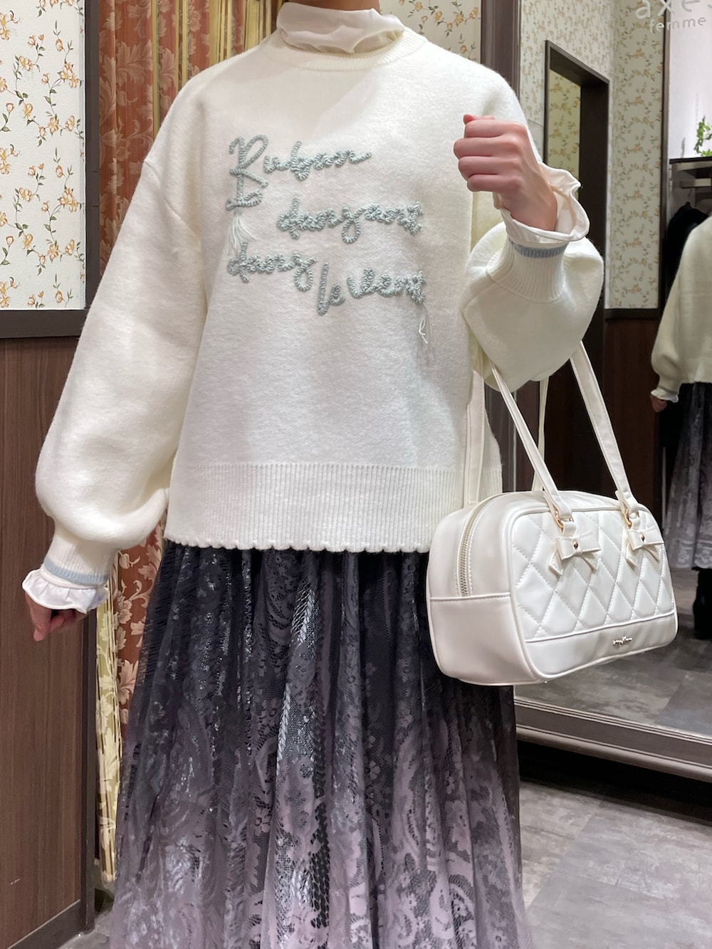 ホワイト系のニット/セーター、ホワイト系のボストンバッグ、ブラウン系のスカートを着用したレディースの冬コーディネートの2枚目の写真