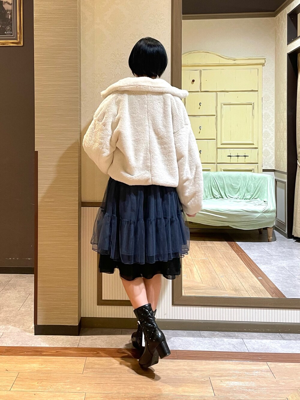 ホワイト系のピーコート、ブルー系のワンピース、ブラック系のブーツを着用したレディースの秋コーディネートの4枚目の写真