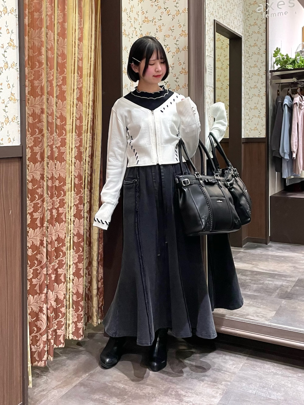 ブラック系のTシャツ/カットソー、ホワイト系のカーディガン/ボレロ、ブラック系のスカートを着用したレディースの冬コーディネートの2枚目の写真