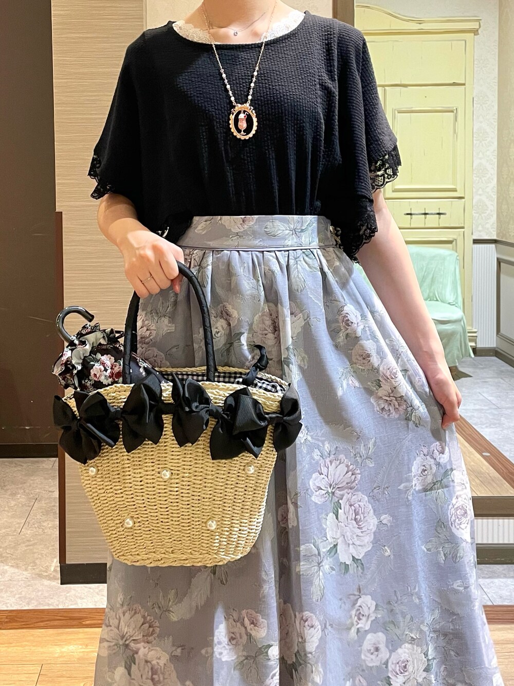 ブラック系のかごバッグ、パープル系のスカート、ブラック系のTシャツ/カットソーを着用したレディースの夏コーディネートの3枚目の写真