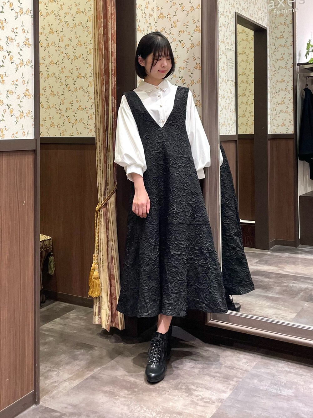 ホワイト系のシャツ/ブラウス、ブラック系のジャンパースカート、ブラック系のブーツを着用したレディースの春コーディネートの3枚目の写真