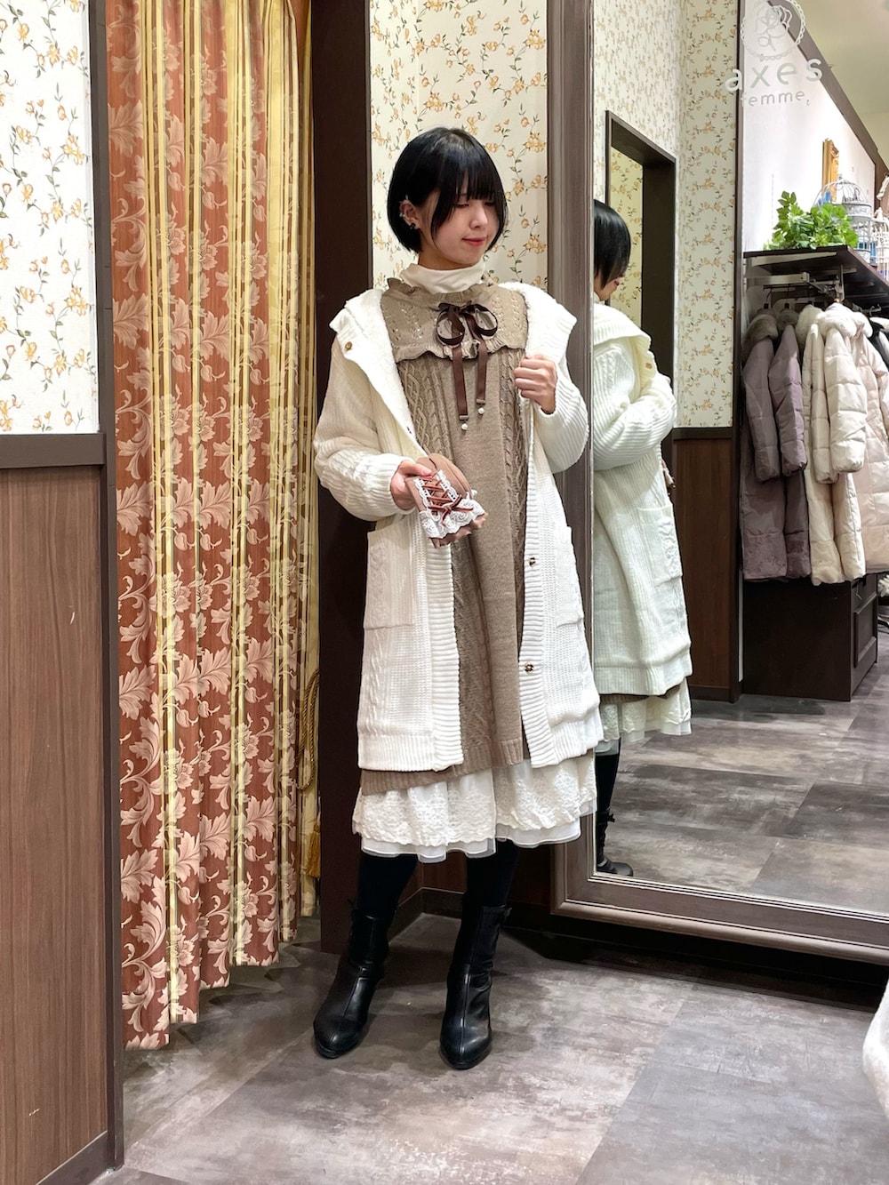 ホワイト系のその他アウター、ブラウン系のワンピース、ブラック系のブーツを着用したレディースの冬コーディネートの3枚目の写真