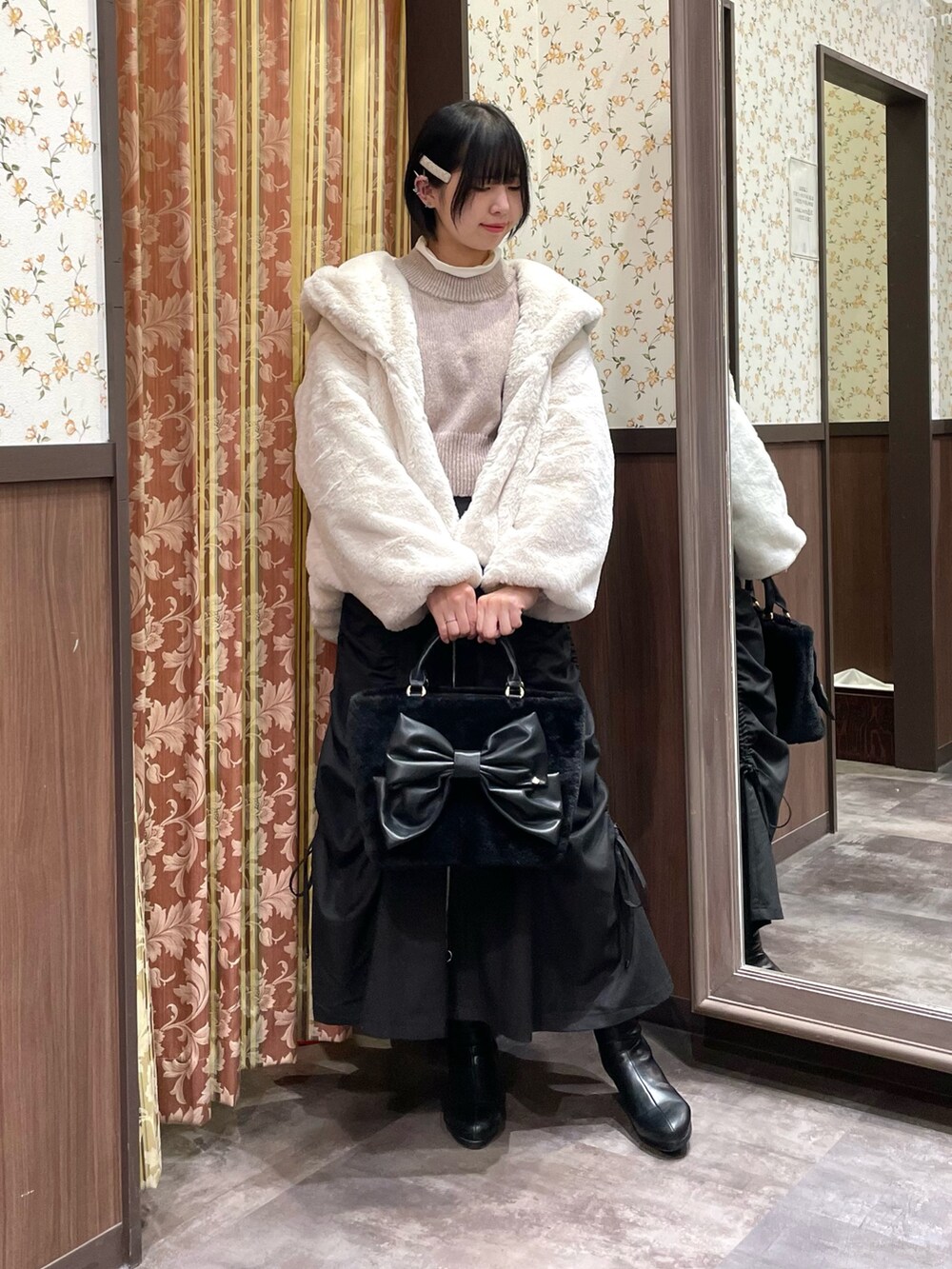 ピンク系のニット/セーター、ブラック系のスカート、ホワイト系のダッフルコートを着用したレディースの冬コーディネートの4枚目の写真