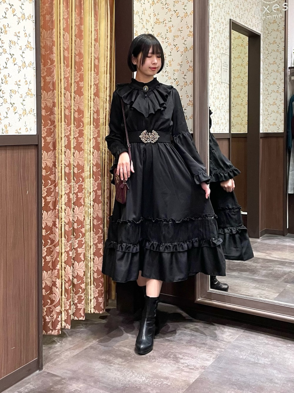 ブラック系のワンピース、ブラック系のブーツ、レッド系のショルダーバッグを着用したレディースの冬コーディネートの3枚目の写真