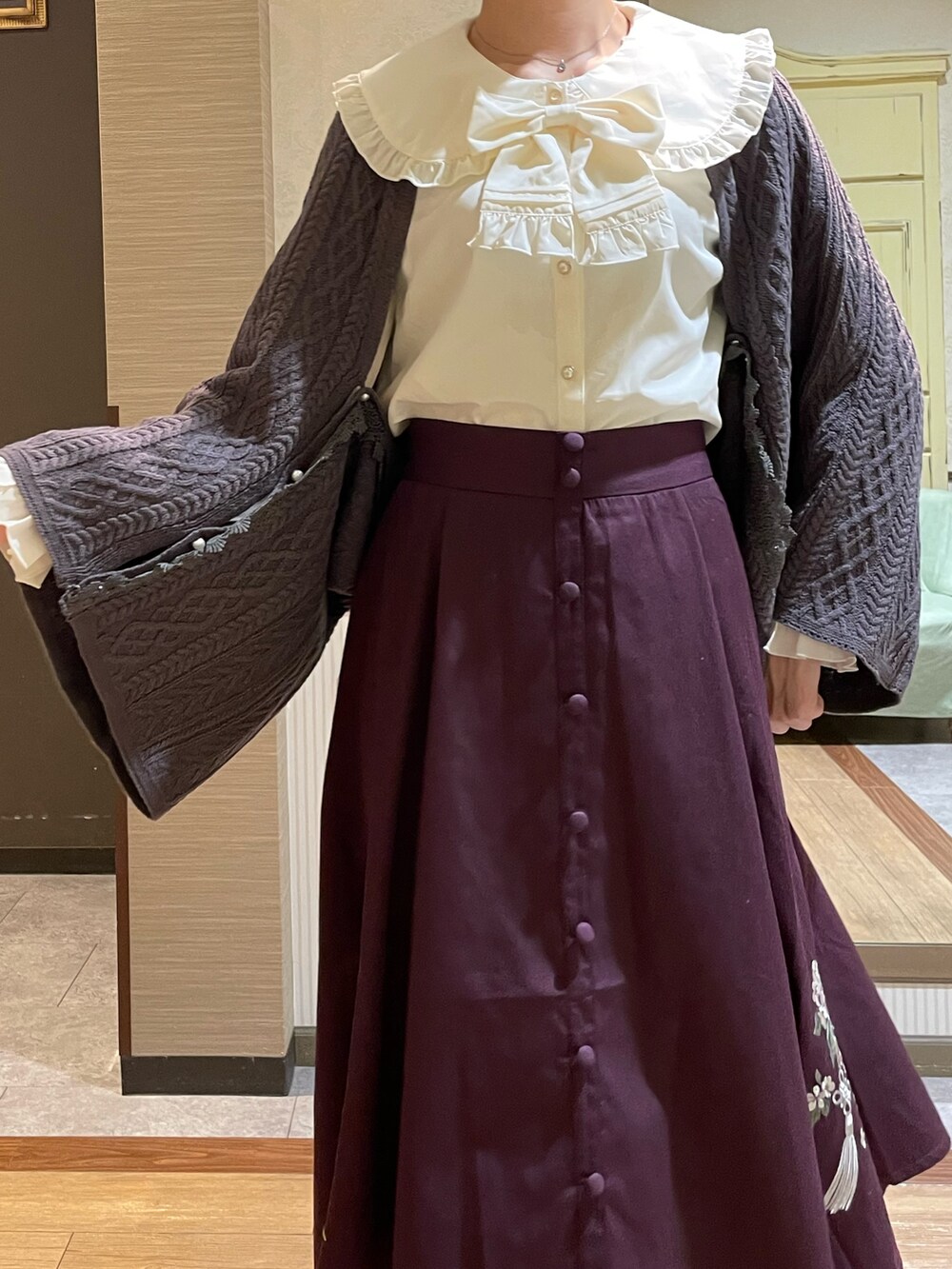 レッド系のスカート、ブラック系のブーツ、ブラック系のショルダーバッグを着用したレディースの秋コーディネートの3枚目の写真