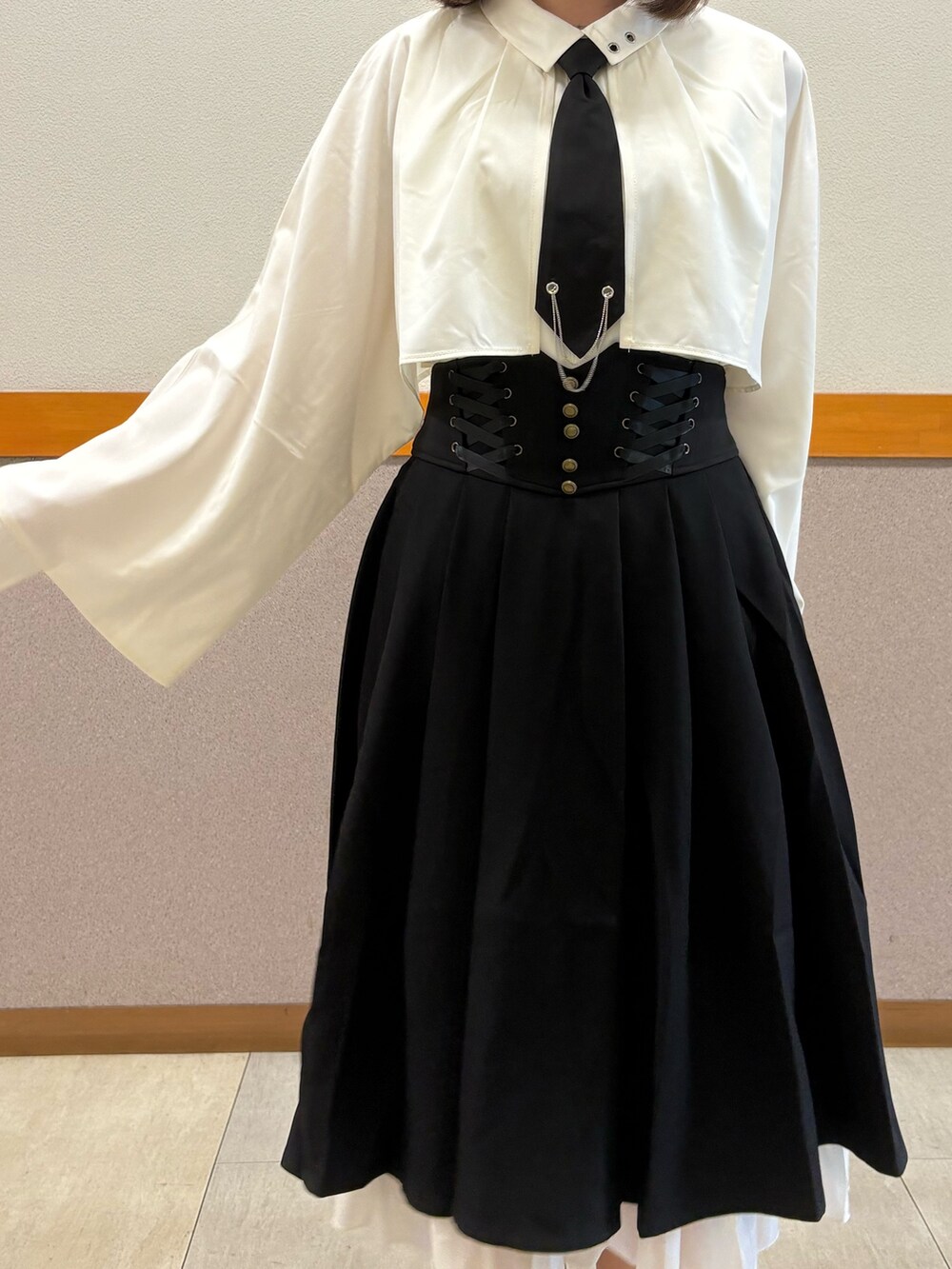 レッド系のトレンチコート、ホワイト系のシャツ/ブラウス、ブラック系のスカートを着用したレディースの秋コーディネートの5枚目の写真