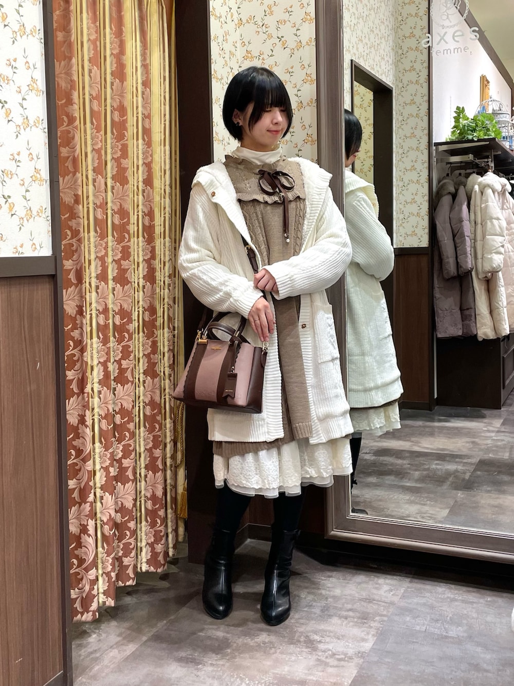 ホワイト系のその他アウター、ブラウン系のワンピース、ブラック系のブーツを着用したレディースの冬コーディネートの2枚目の写真
