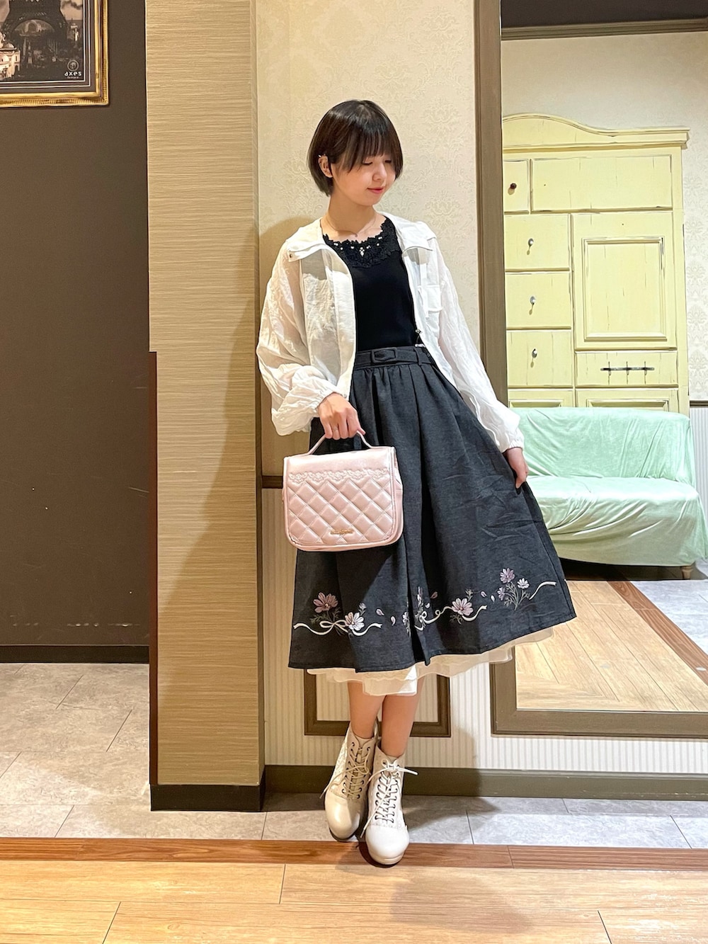 ホワイト系のブルゾン、ブラック系のタンクトップ、ブラック系のスカートを着用したレディースの秋コーディネートの4枚目の写真