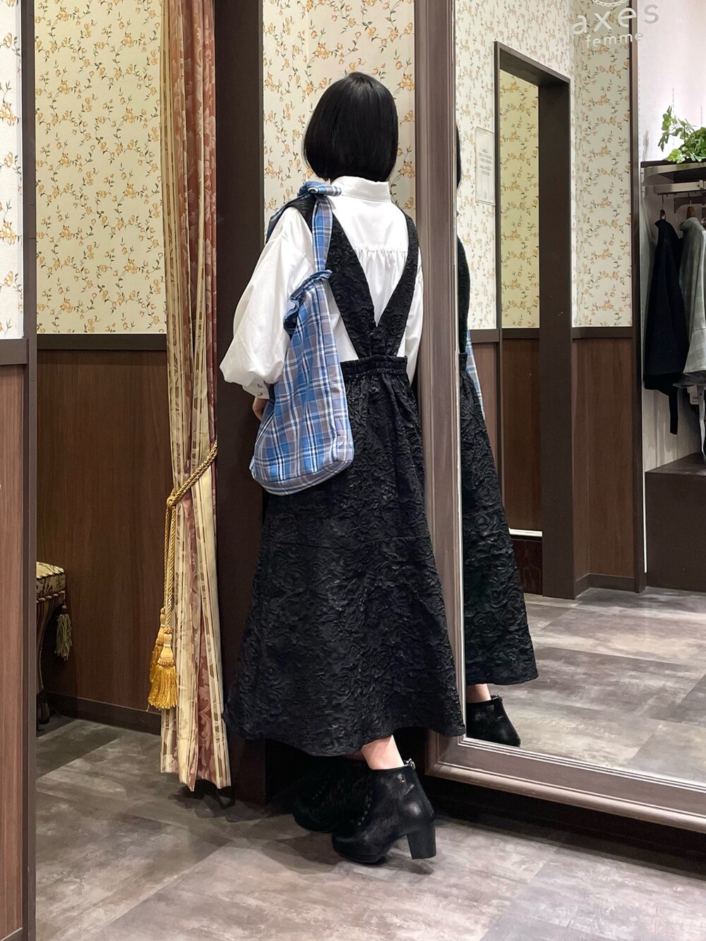 ホワイト系のシャツ/ブラウス、ブラック系のジャンパースカート、ブラック系のブーツを着用したレディースの春コーディネートの5枚目の写真