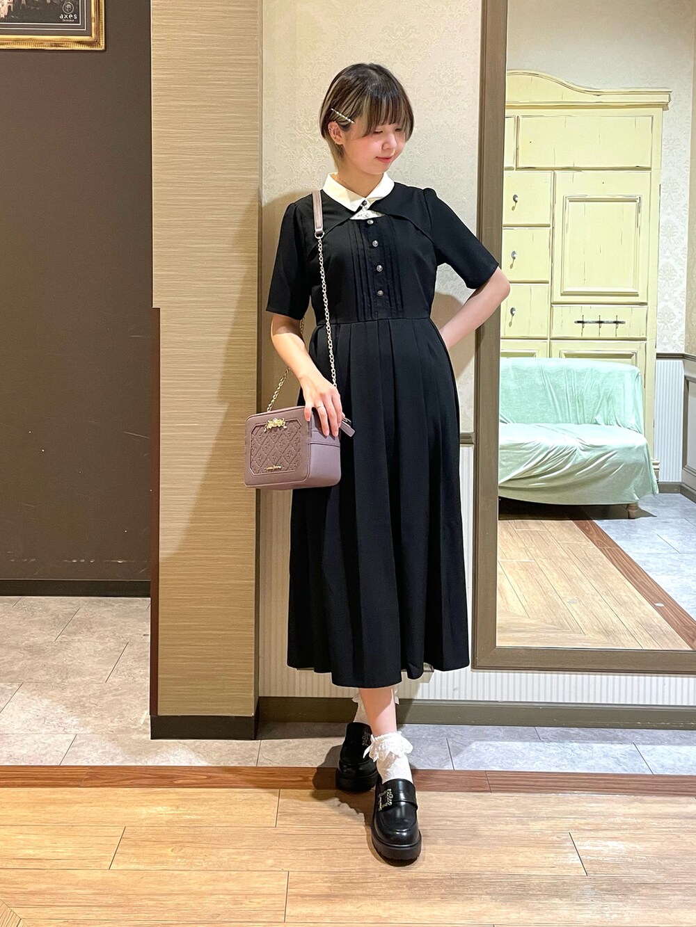 パープル系のショルダーバッグ、ブラック系のワンピース、ホワイト系のタンクトップを着用したレディースの夏コーディネートの2枚目の写真