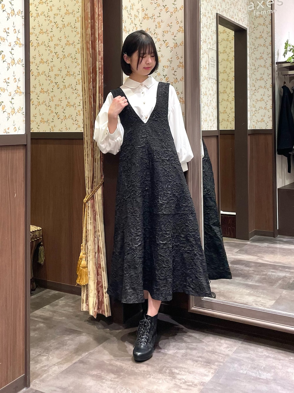 ホワイト系のシャツ/ブラウス、ブラック系のジャンパースカート、ブラック系のブーツを着用したレディースの春コーディネートの2枚目の写真