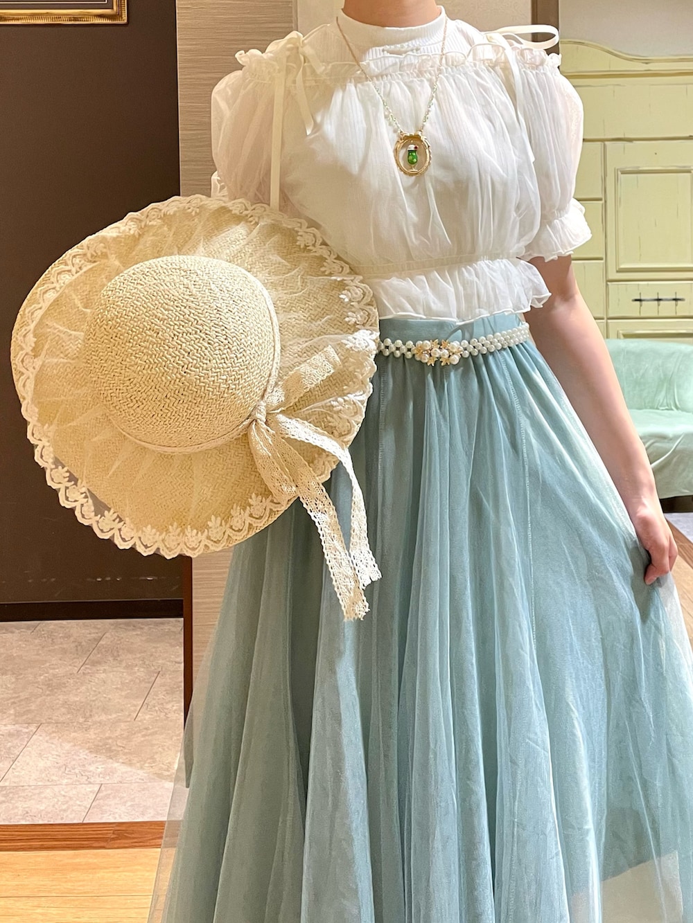 ホワイト系のタンクトップ、ホワイト系のサンダル、グリーン系のスカートを着用したレディースの夏コーディネートの4枚目の写真