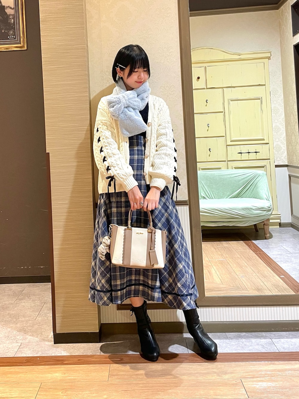 ブラック系のブーツ、ホワイト系のカーディガン/ボレロ、ブルー系のスカートを着用したレディースの秋コーディネートの2枚目の写真