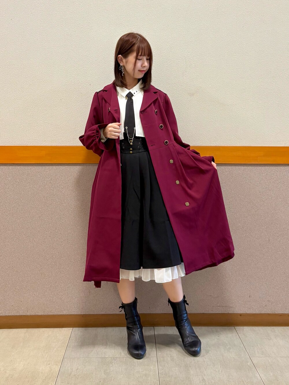 レッド系のトレンチコート、ホワイト系のシャツ/ブラウス、ブラック系のスカートを着用したレディースの秋コーディネートの8枚目の写真