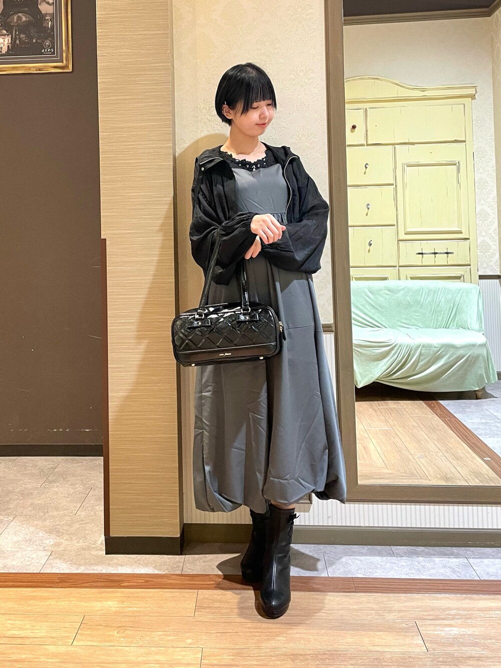 ブラック系のブルゾン、ブラック系のタンクトップ、グレー系のジャンパースカートを着用したレディースの秋コーディネートの2枚目の写真