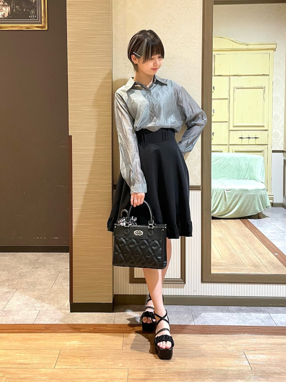 ブラック系のショルダーバッグ、ブラック系のスカート、グリーン系のタンクトップを着用したレディースの夏コーディネートの2枚目の写真