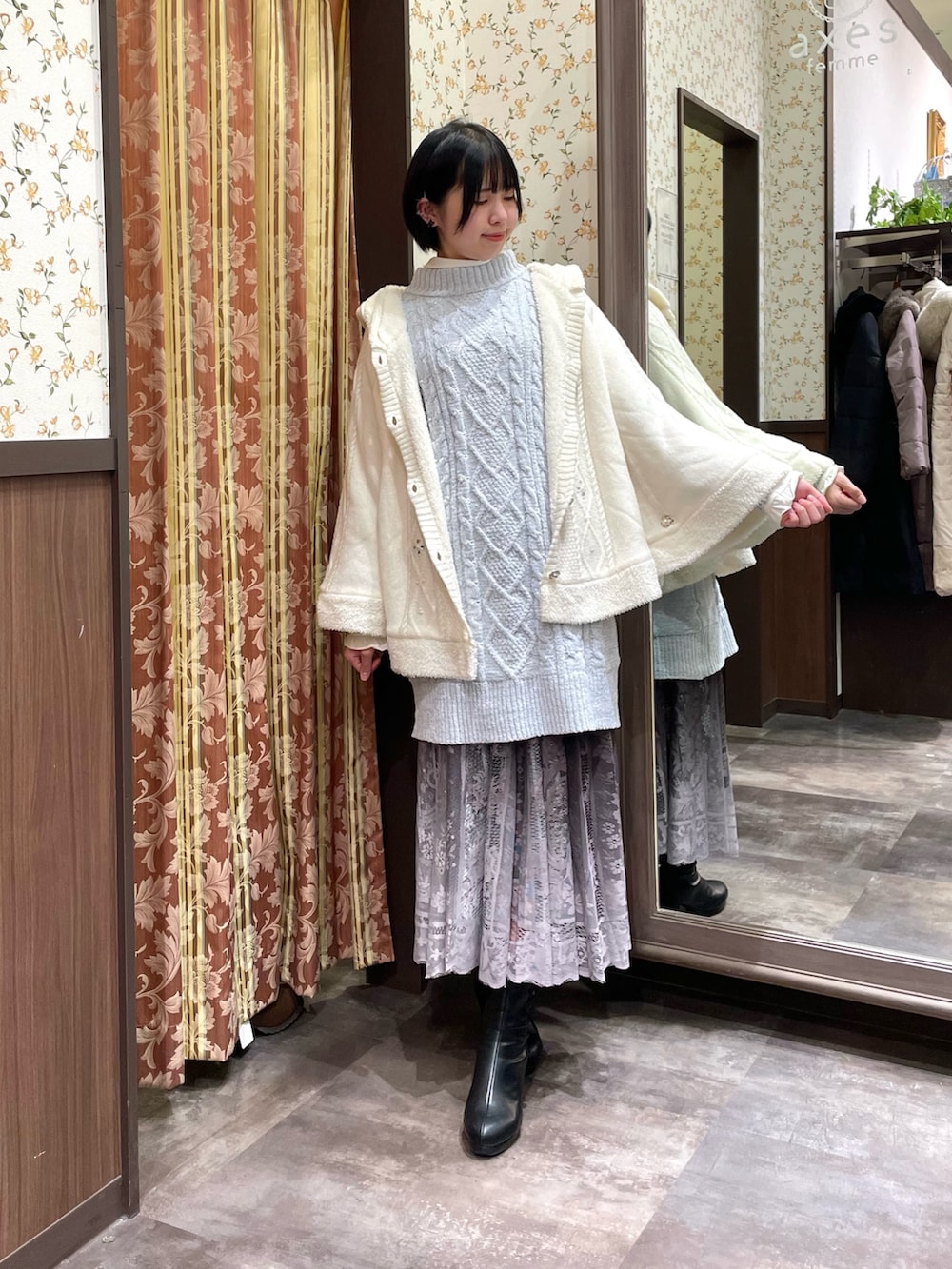 ブラック系のブーツ、ブラウン系のスカート、ホワイト系のボストンバッグを着用したレディースの冬コーディネートの2枚目の写真