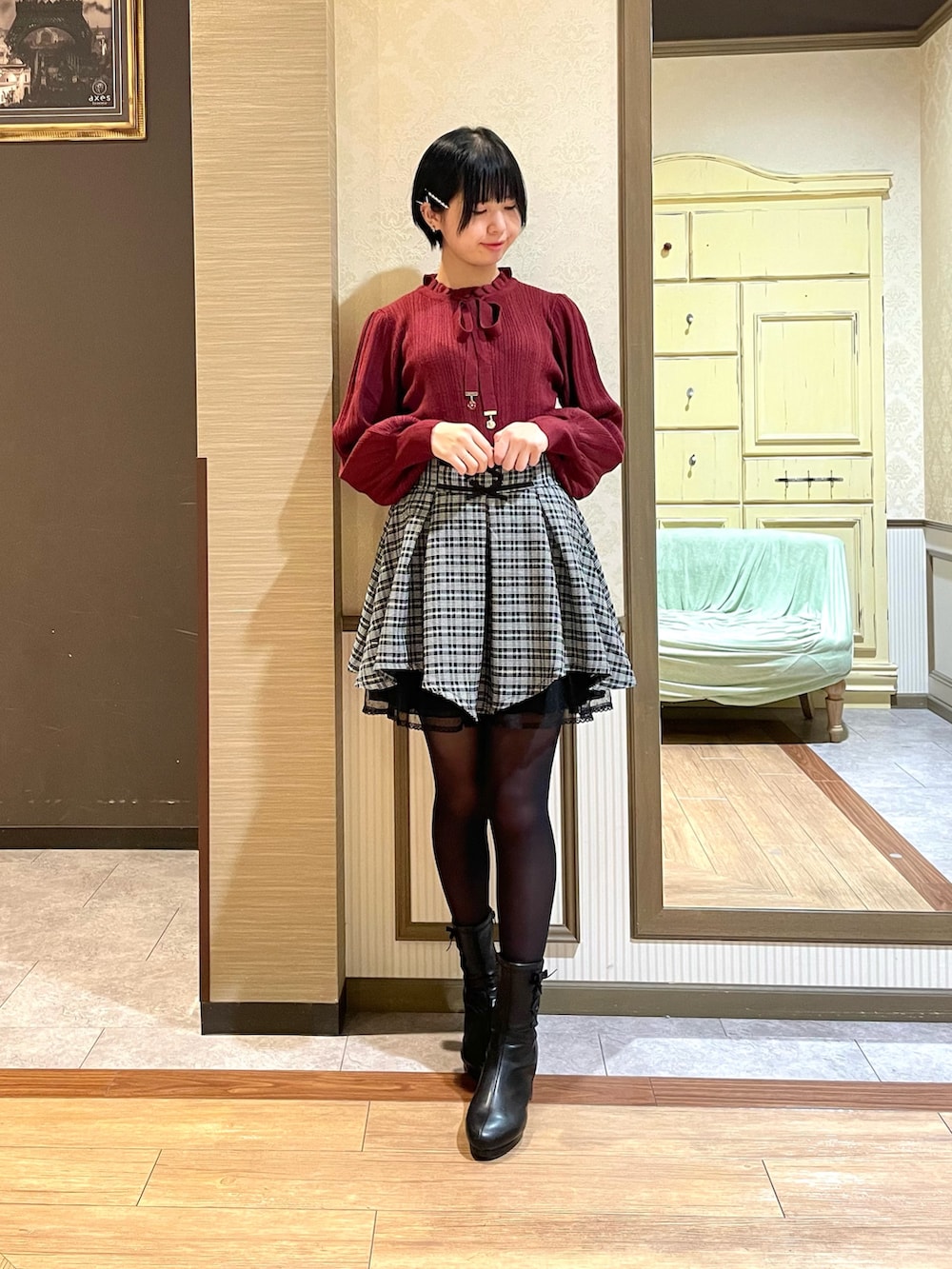 レッド系のニット/セーター、ブラック系のその他アウター、ブラック系のブーツを着用したレディースの秋コーディネートの6枚目の写真