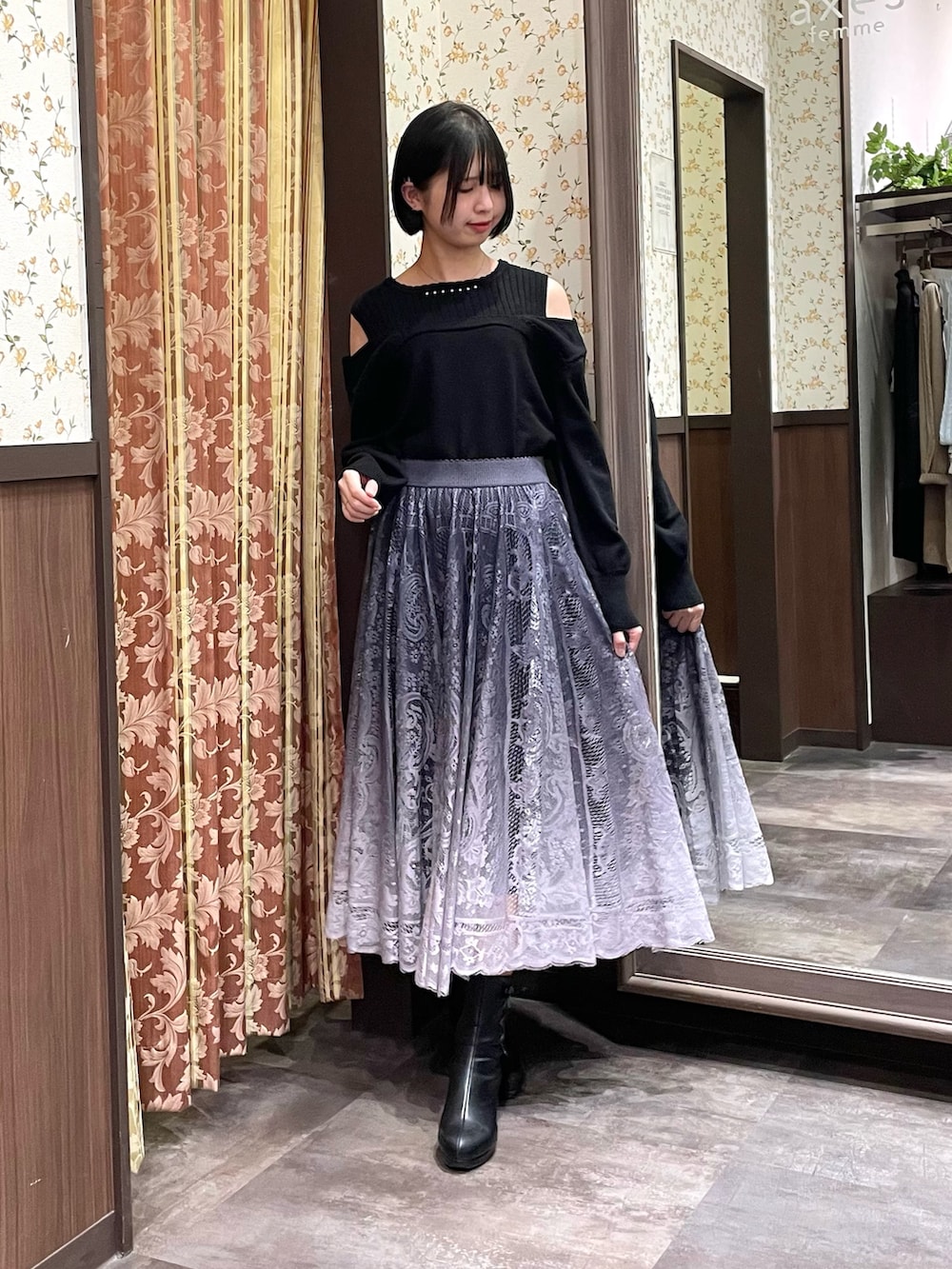 ブラック系のニット/セーター、グレー系のスカート、ブラック系のブーツを着用したレディースの冬コーディネートの2枚目の写真