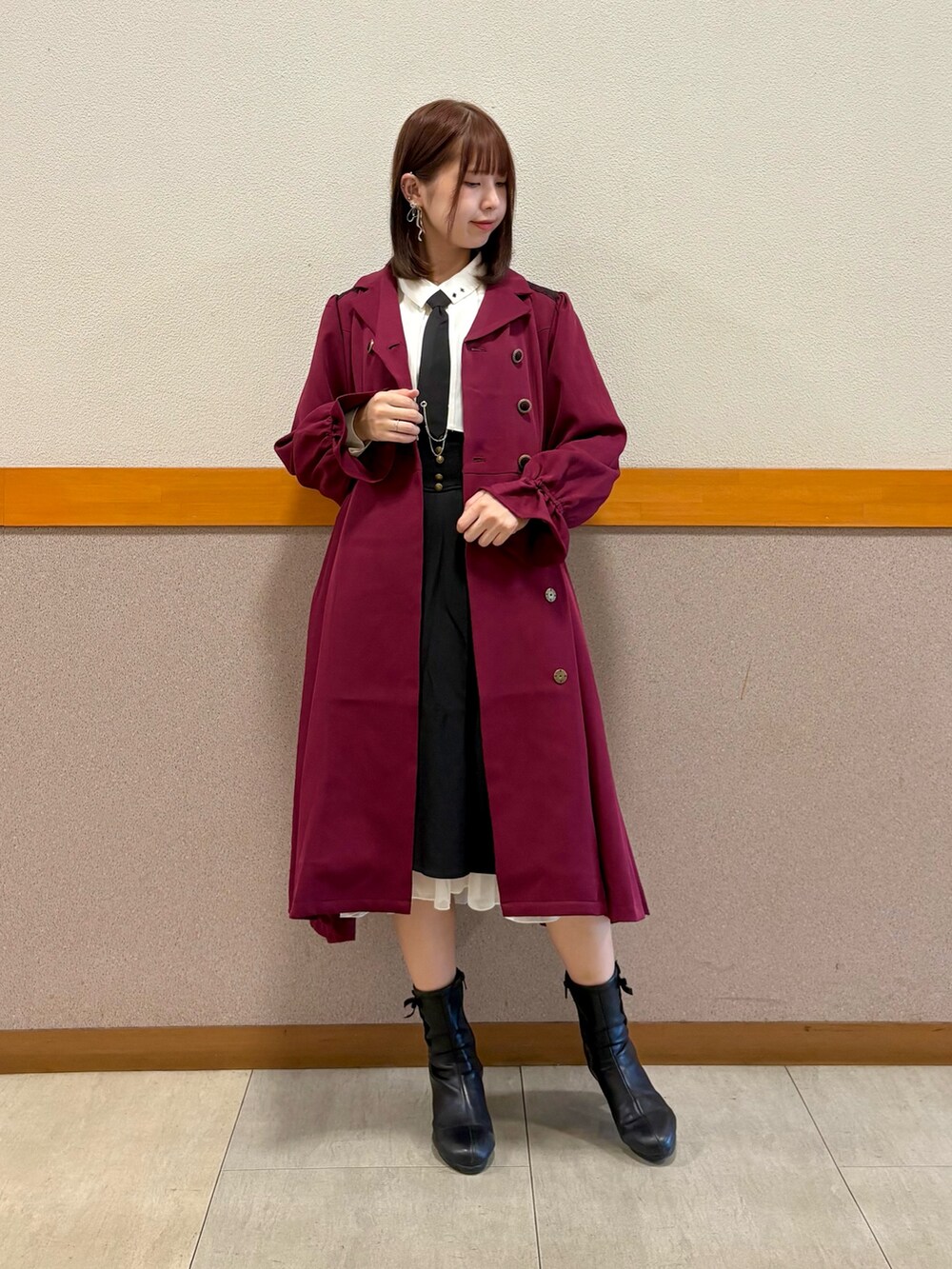 レッド系のトレンチコート、ホワイト系のシャツ/ブラウス、ブラック系のスカートを着用したレディースの秋コーディネートの7枚目の写真