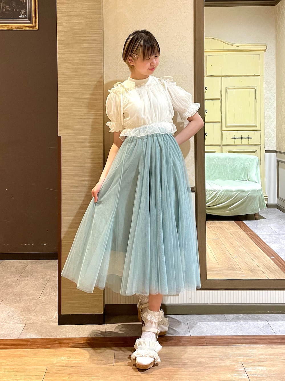 ホワイト系のタンクトップ、ホワイト系のサンダル、グリーン系のスカートを着用したレディースの夏コーディネートの5枚目の写真