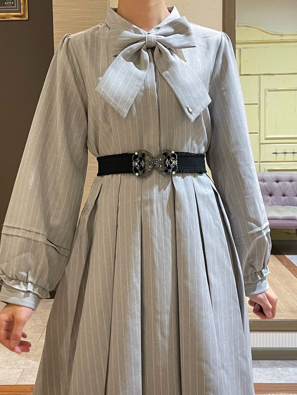 グレー系のワンピース、ブラック系のショルダーバッグ、ブラック系のブーツを着用したレディースの秋コーディネートの8枚目の写真