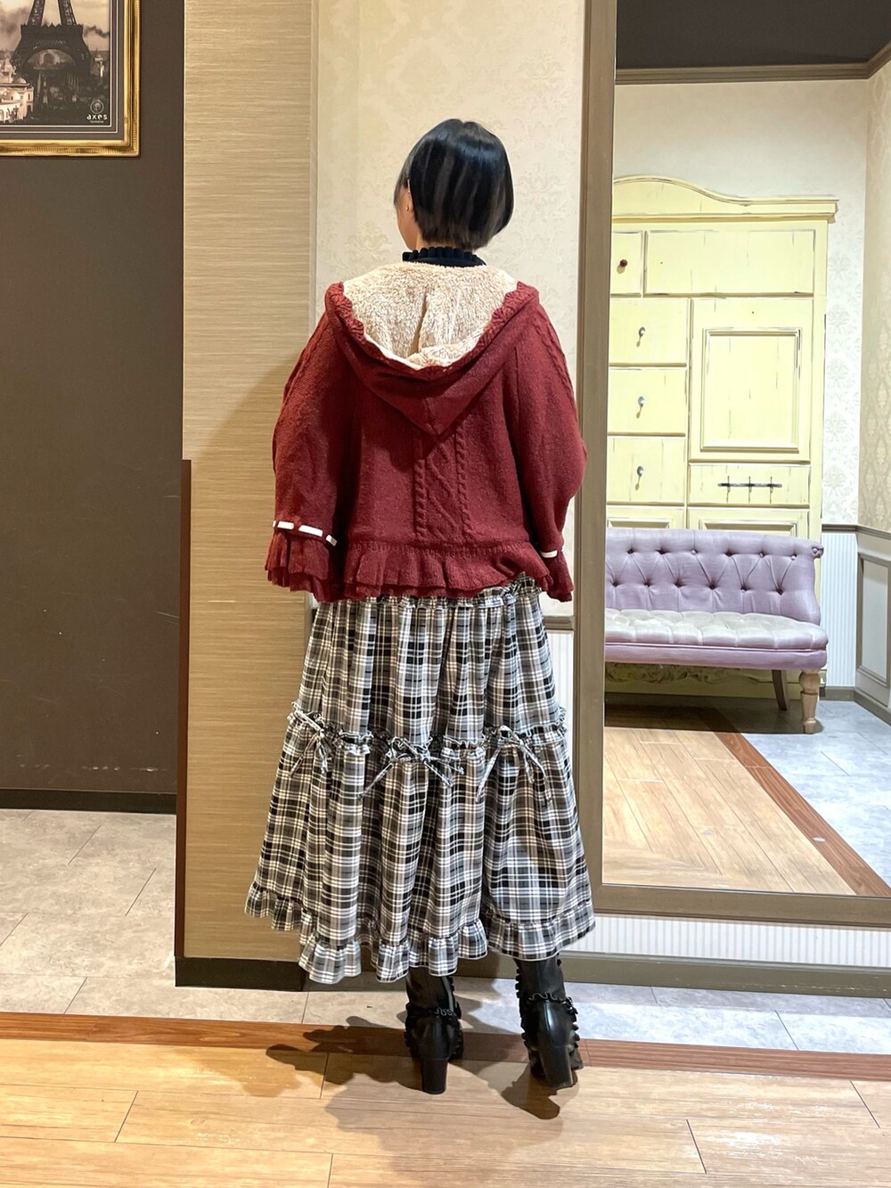 ブラック系のニット/セーター、レッド系のポンチョ、ブラック系のトートバッグを着用したレディースの秋コーディネートの5枚目の写真