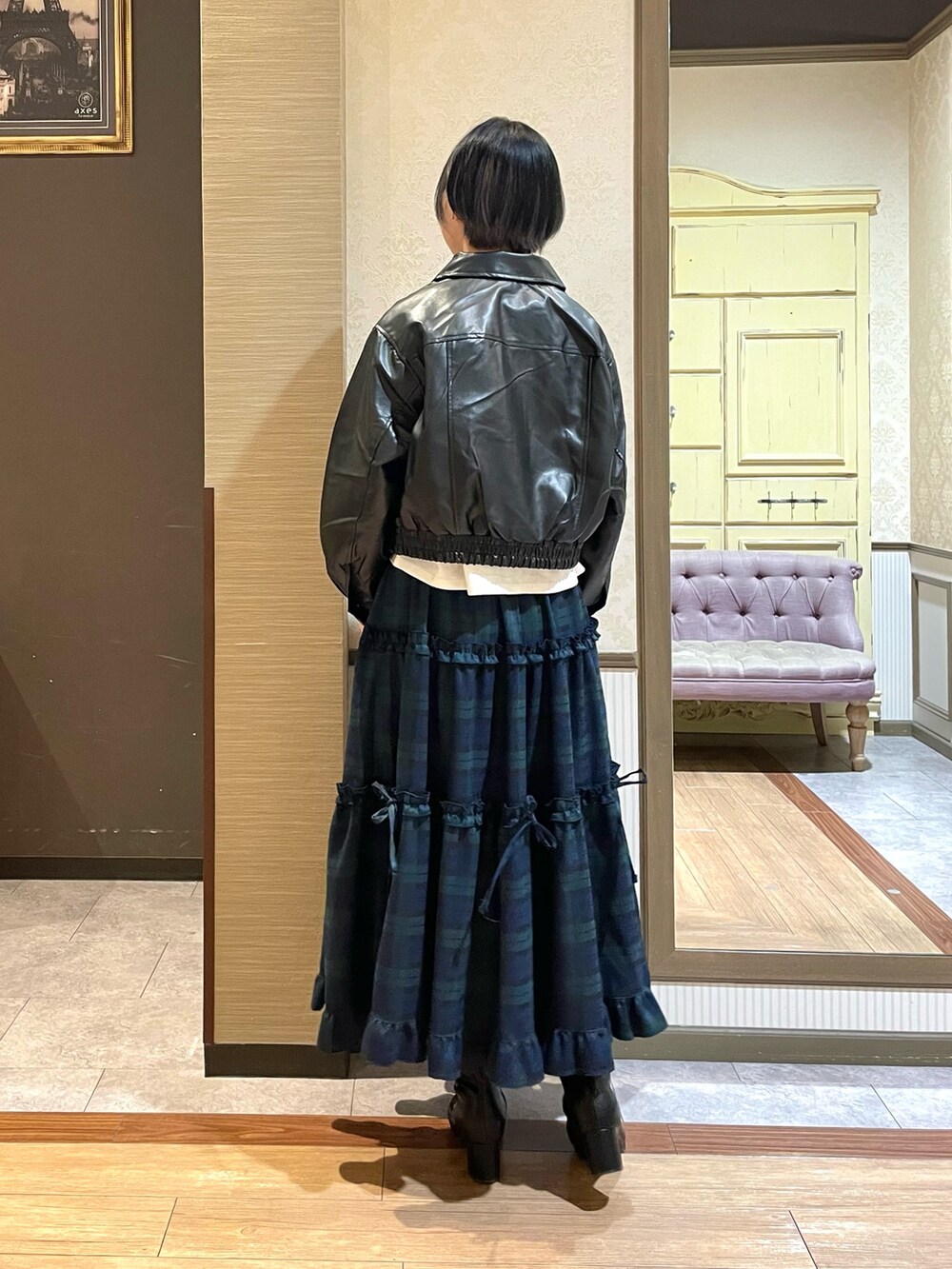 ブラック系のショルダーバッグ、ブラック系のブーツ、グリーン系のスカートを着用したレディースの秋コーディネートの5枚目の写真