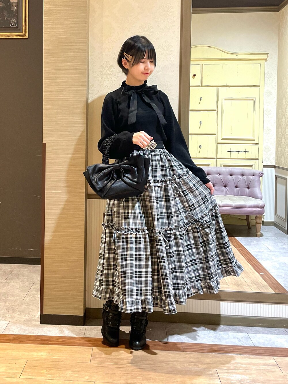 ブラック系のニット/セーター、レッド系のポンチョ、ブラック系のトートバッグを着用したレディースの秋コーディネートの6枚目の写真