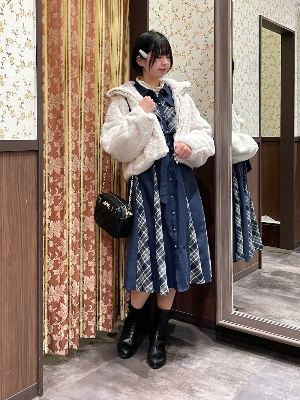 ホワイト系のピーコート、ブルー系のワンピース、ブラック系のブーツを着用したレディースの冬コーディネートの2枚目の写真