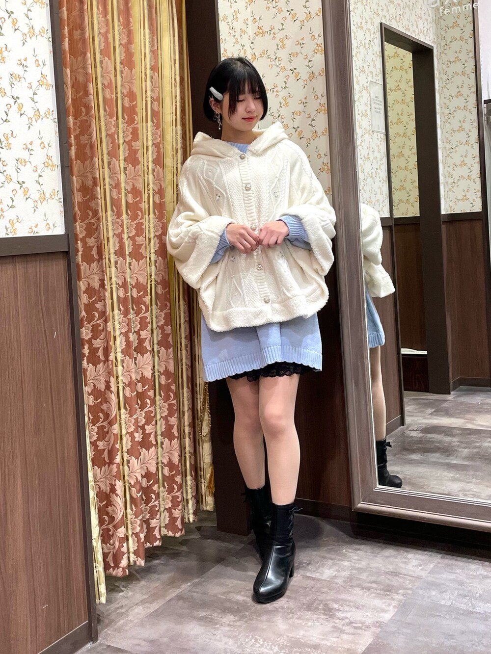 ブルー系のチュニック、ホワイト系のポンチョ、ホワイト系のショルダーバッグを着用したレディースの冬コーディネートの6枚目の写真