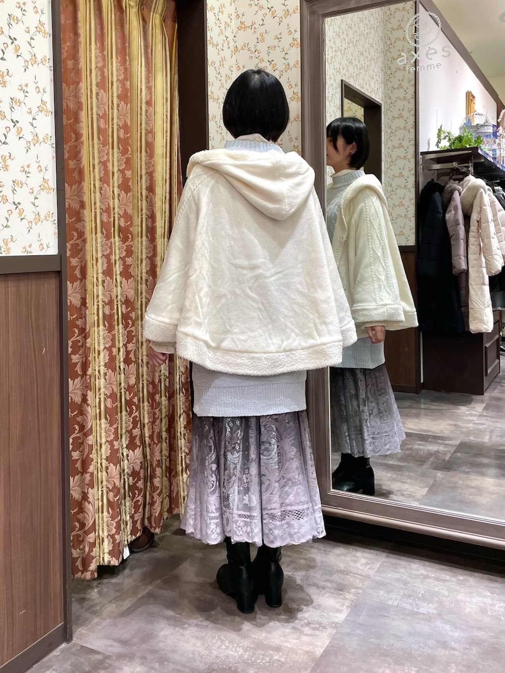 ブラック系のブーツ、ブラウン系のスカート、ホワイト系のボストンバッグを着用したレディースの冬コーディネートの3枚目の写真