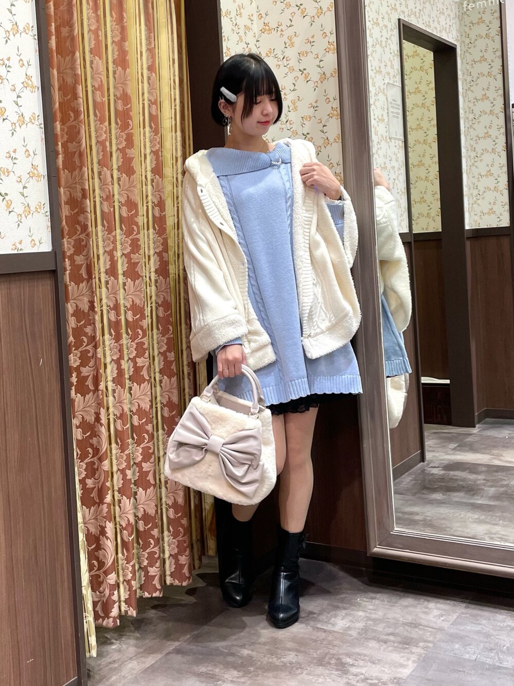 ブルー系のチュニック、ホワイト系のポンチョ、ホワイト系のショルダーバッグを着用したレディースの冬コーディネートの4枚目の写真