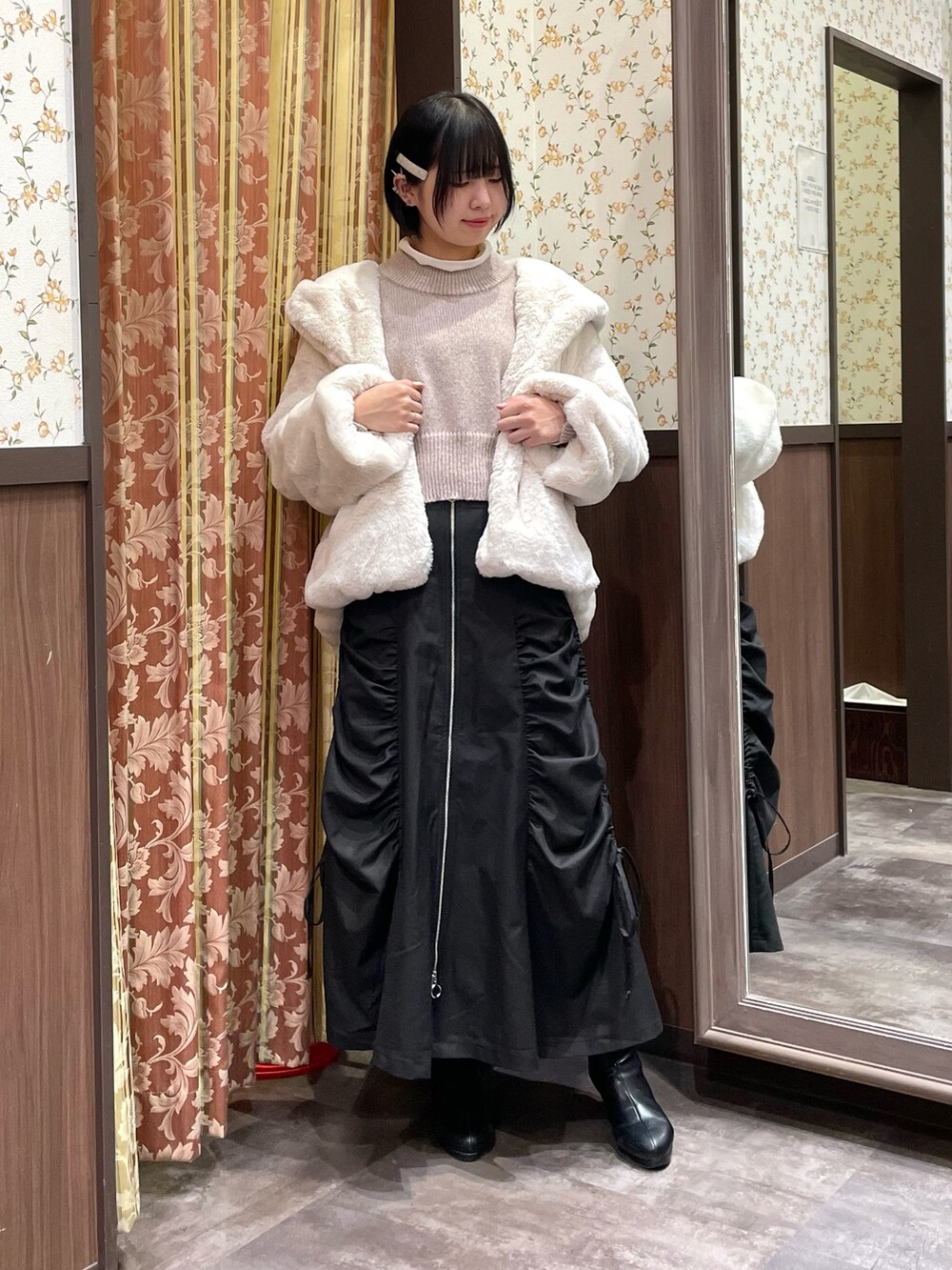 ピンク系のニット/セーター、ブラック系のスカート、ホワイト系のダッフルコートを着用したレディースの冬コーディネートの5枚目の写真