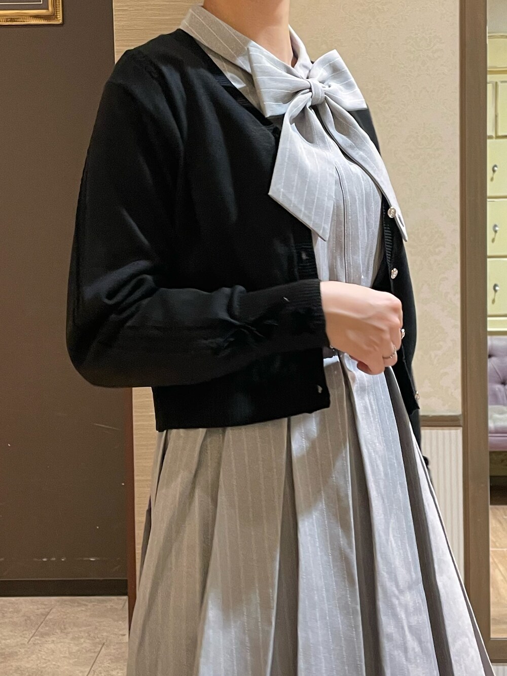 グレー系のワンピース、ブラック系のショルダーバッグ、ブラック系のブーツを着用したレディースの秋コーディネートの4枚目の写真