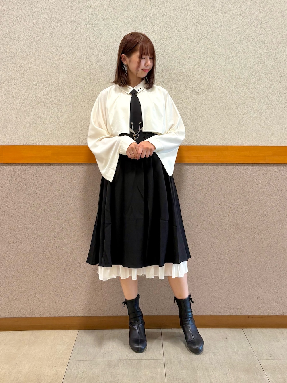 レッド系のトレンチコート、ホワイト系のシャツ/ブラウス、ブラック系のスカートを着用したレディースの秋コーディネートの2枚目の写真