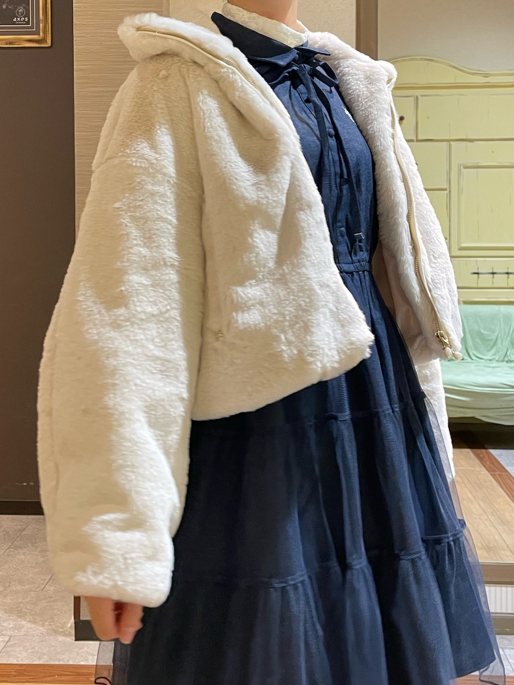 ホワイト系のピーコート、ブルー系のワンピース、ブラック系のブーツを着用したレディースの秋コーディネートの5枚目の写真