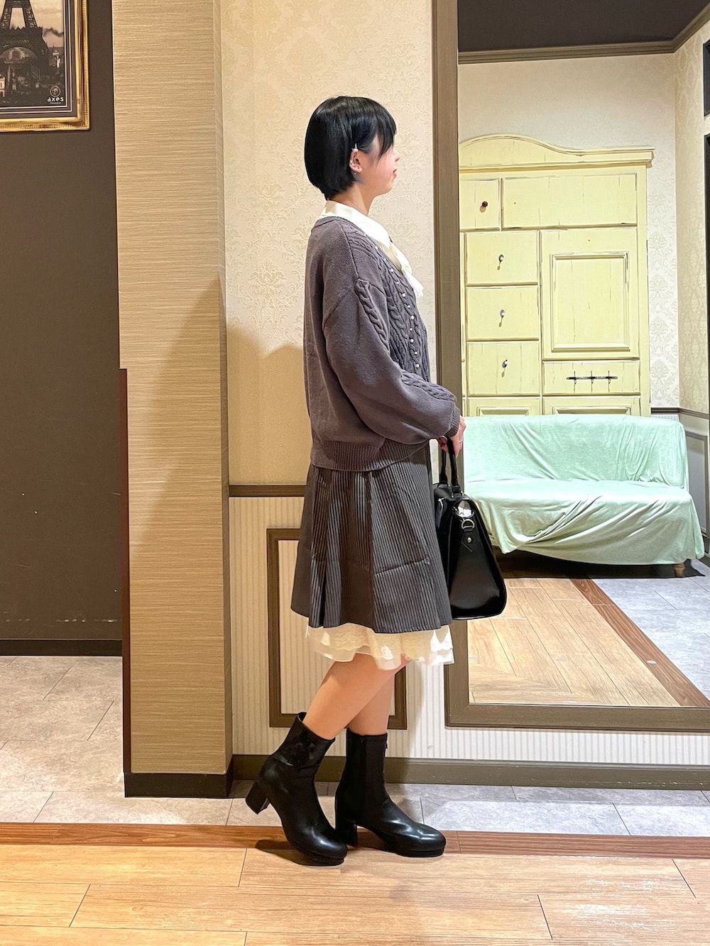 ブラック系のショルダーバッグ、ブラック系のブーツ、グレー系のカーディガン/ボレロを着用したレディースの秋コーディネートの2枚目の写真